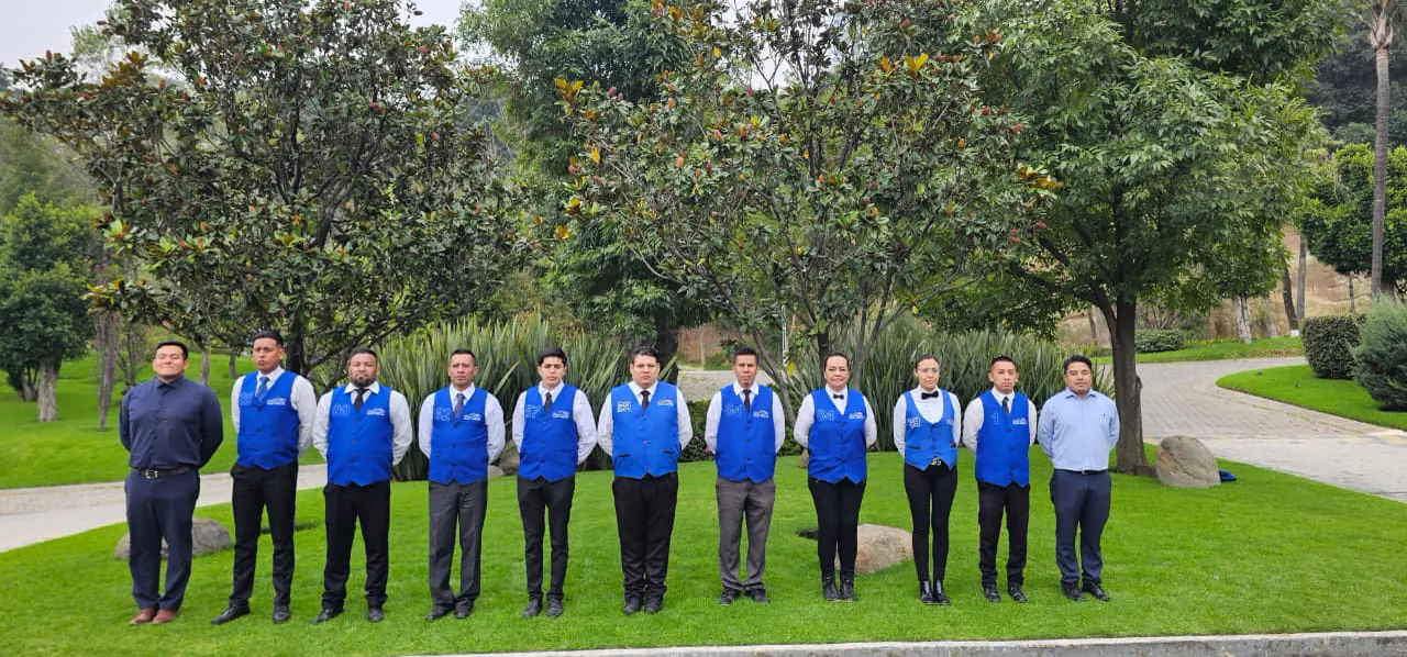 Equipo mediano de valet uniformado formado en un jardín