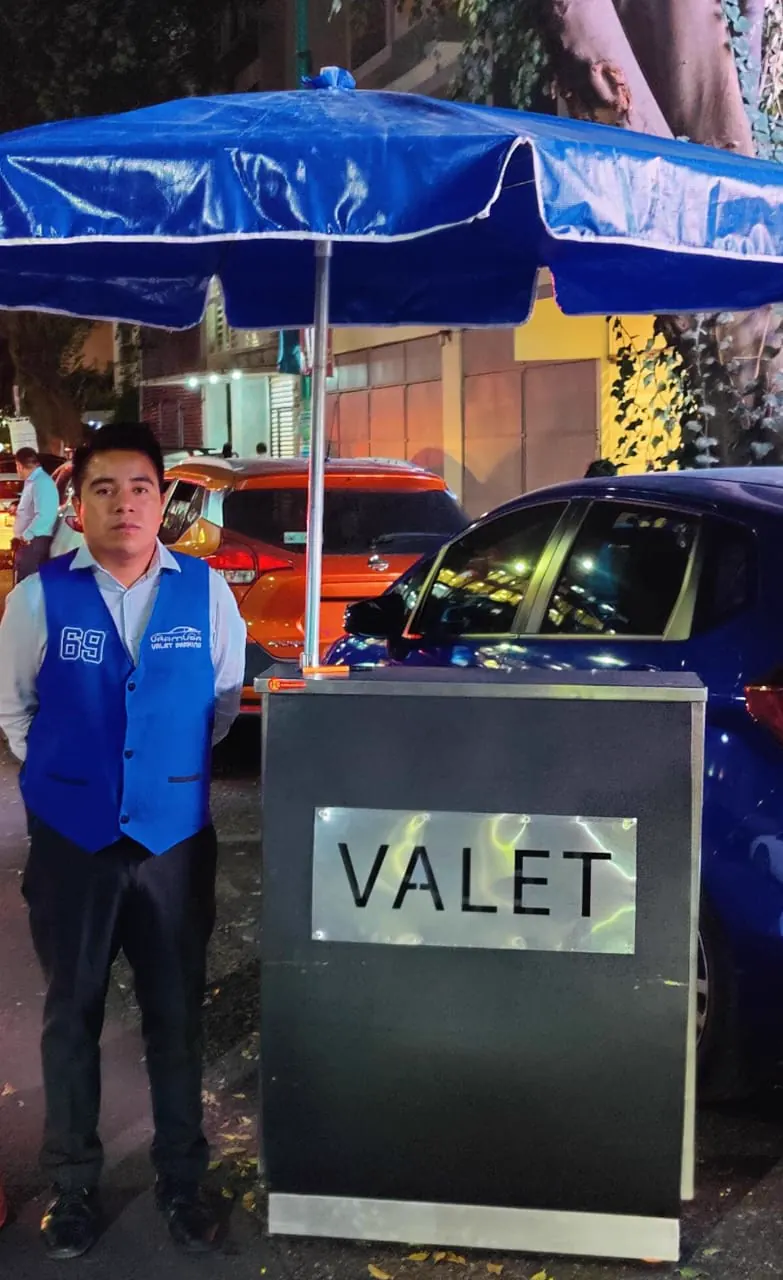 Colaborador de valet junto a un módulo de servicio durante la noche